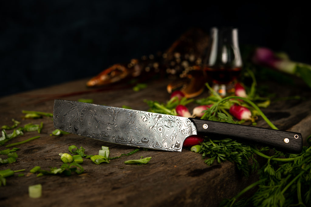 Couteau de chef en acier damas posé sur un plan de travail en bois